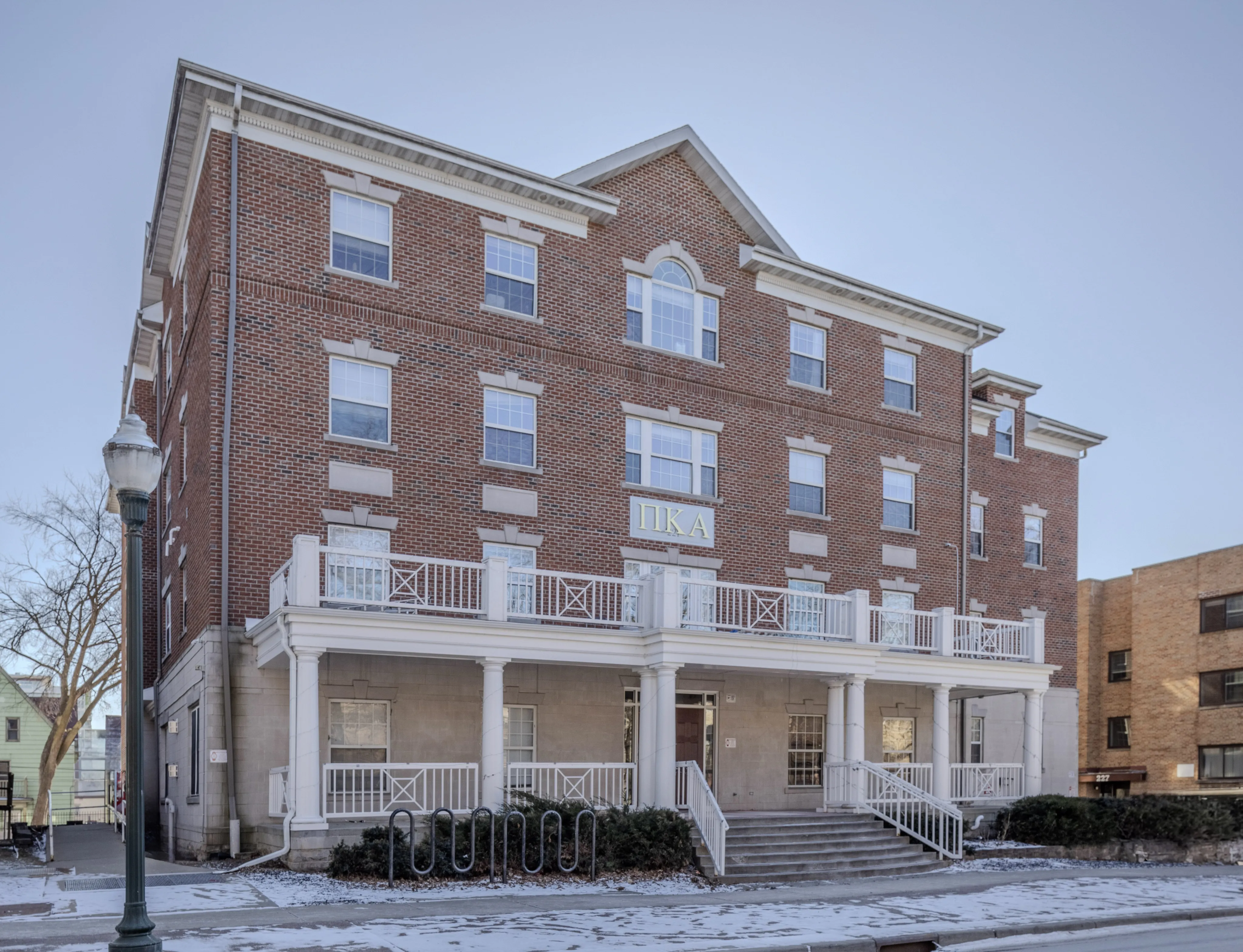 Charming brick apartment building with classic architecture, featuring large windows and a welcoming front porch.