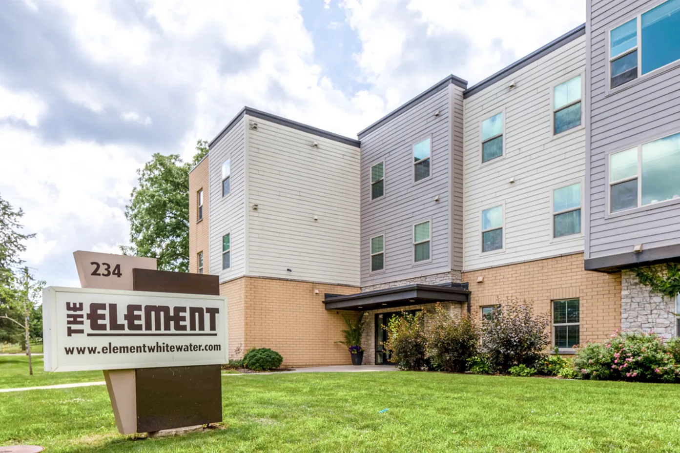 Modern apartment building entrance with lush landscaping and a prominent sign reading 'The Element' located at 234.