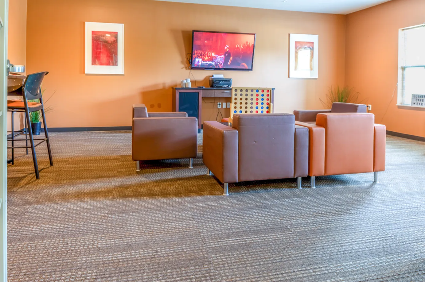 Inviting lounge area featuring modern leather chairs, a wall-mounted TV, and vibrant artwork, ideal for relaxing or entertaining.