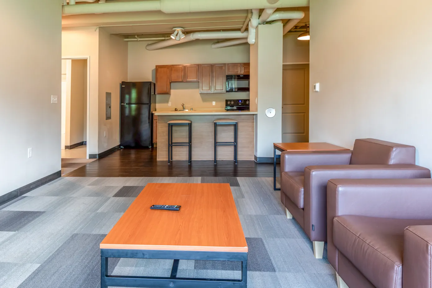 Modern apartment interior featuring an open-concept living room with plush sofas, a sleek kitchen with bar seating, and elegant finishes.