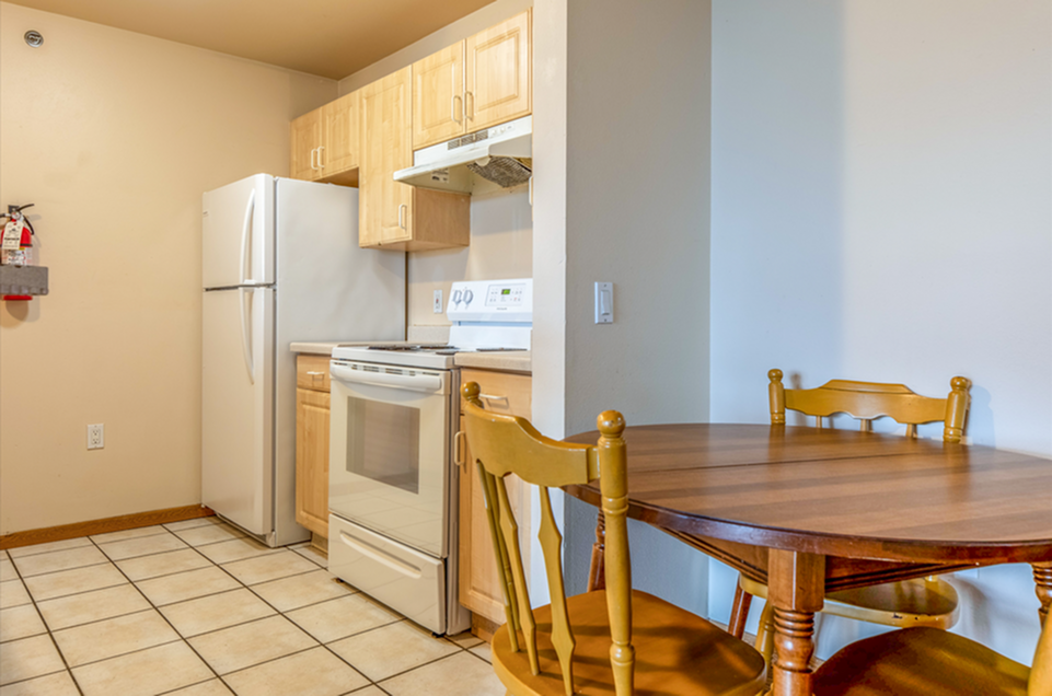 Charming kitchen with modern appliances, cozy dining area, and warm wooden cabinets, perfect for intimate meals.