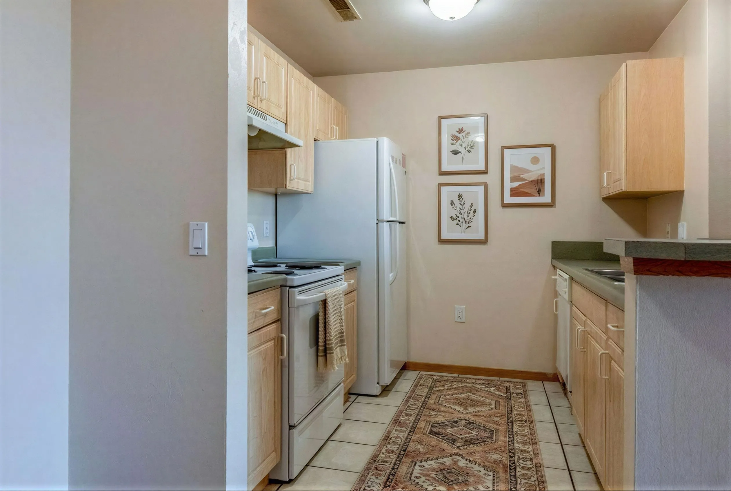 Cozy kitchen with modern appliances, light wood cabinets, and artful decor creating a warm, inviting atmosphere.