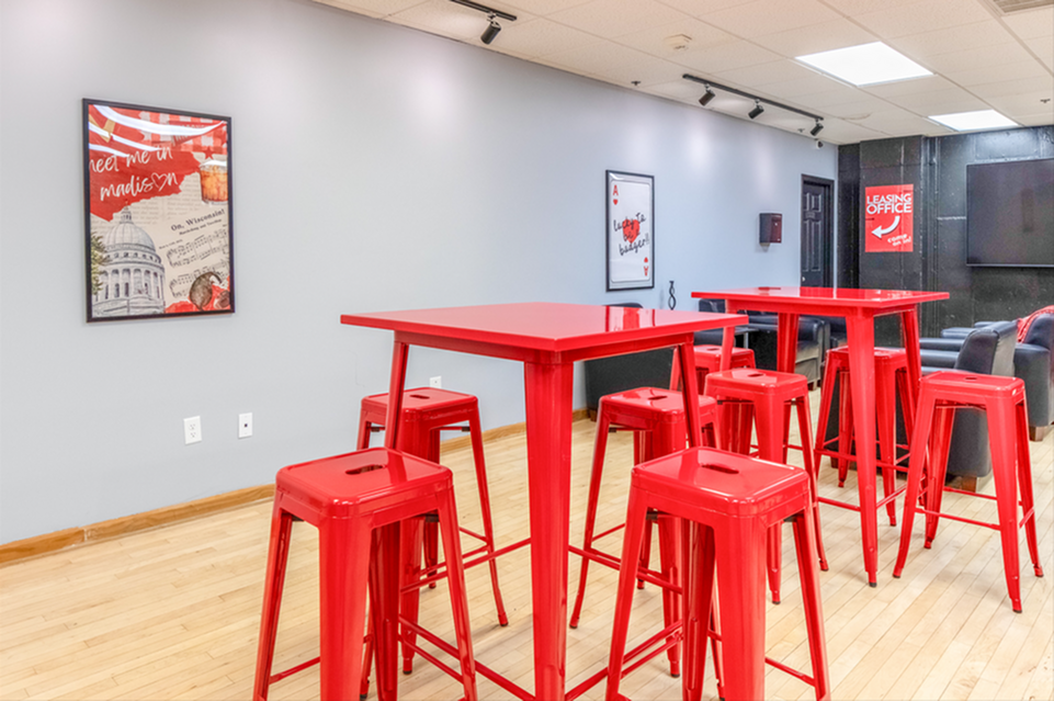 Vibrant communal area featuring stylish red high tables and stools, perfect for social gatherings or casual meetings.