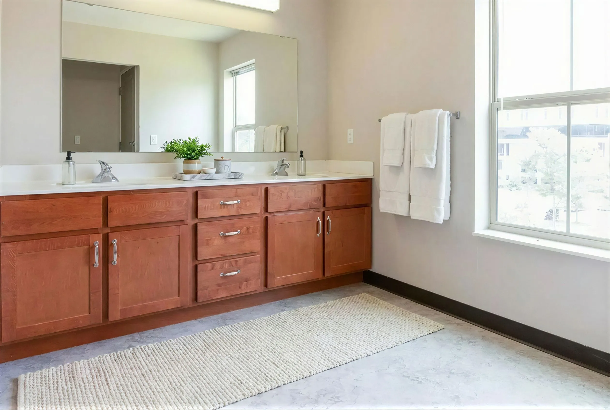 Bright and inviting bathroom with dual sinks, elegant wooden cabinetry, and a large mirror perfect for morning routines.