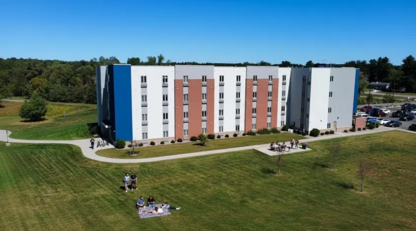 Modern apartment building with a stylish facade, surrounded by lush green lawns and vibrant outdoor spaces.