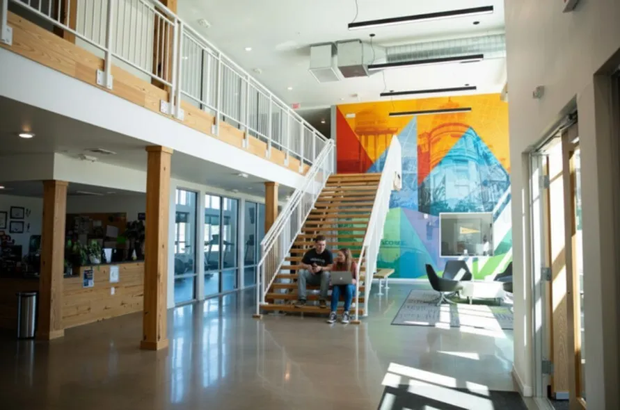 Modern apartment lobby with vibrant mural, open seating, and stylish staircase.