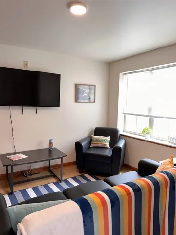 2 Bedroom Model Unit fully furnished apartment including couch, accent chair, flat screen tv, coffee table and side table. Huge window looking over lake st