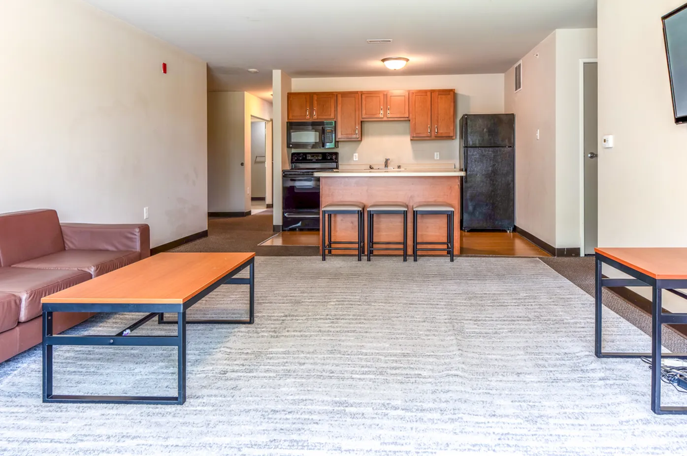 Modern open-plan living room with a cozy sofa, sleek coffee table, and dining area connected to a stylish kitchen with bar seating.