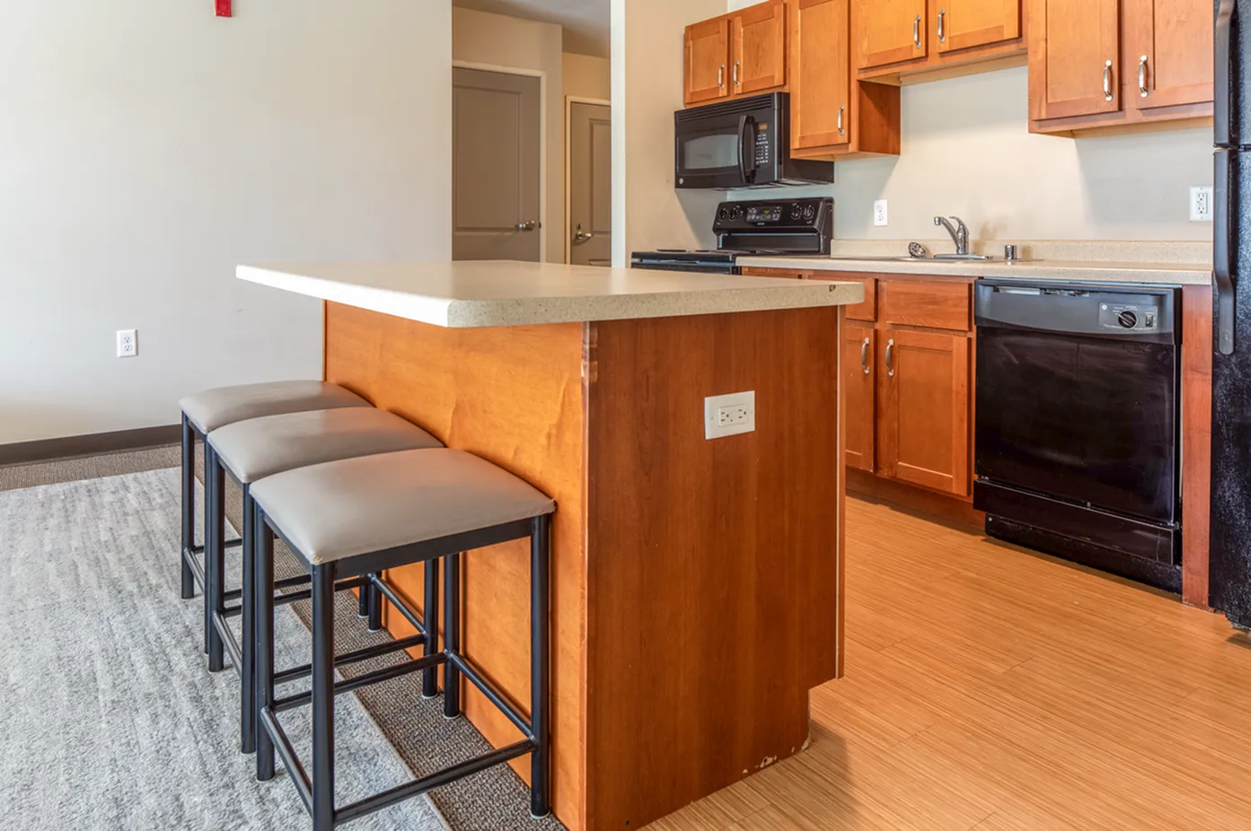 Contemporary kitchen featuring sleek wood cabinets, modern appliances, and a chic breakfast bar with cushioned stools.