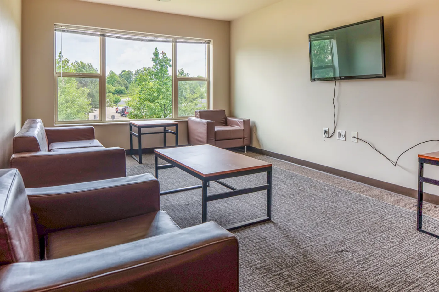 Inviting living space with large window views, featuring cozy modern seating and a mounted TV.