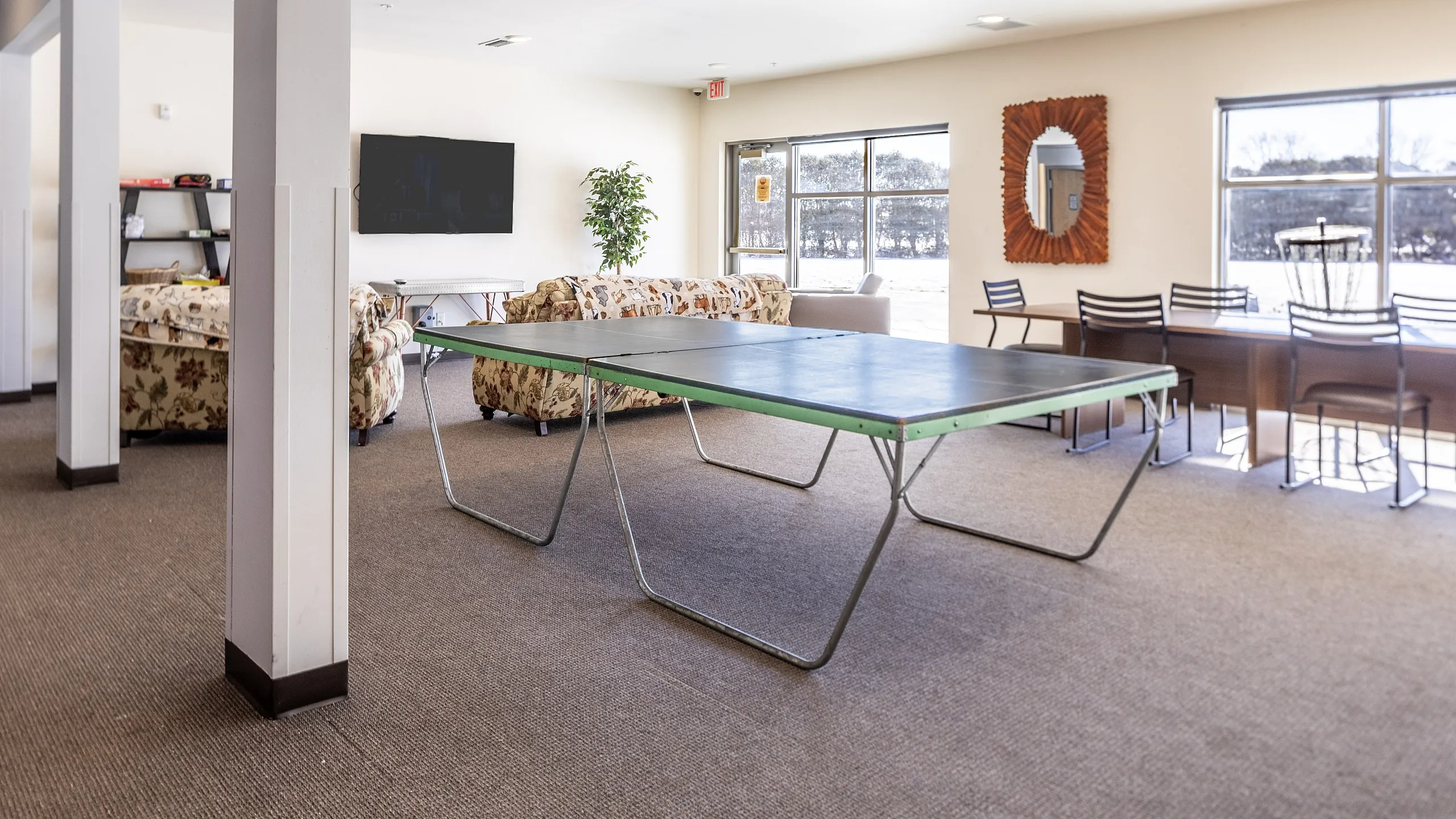 Inviting communal space featuring a ping pong table, comfortable seating, and a bright window view.