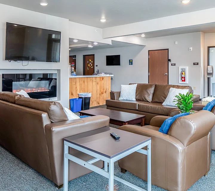 Inviting common area featuring cozy brown leather seating, modern fireplace, and large TV, perfect for relaxing and socializing.