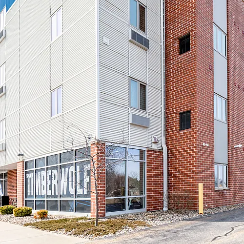 Modern brick and siding mid-rise apartment building with sleek design and large windows, featuring a well-maintained exterior and inviting entrance area.