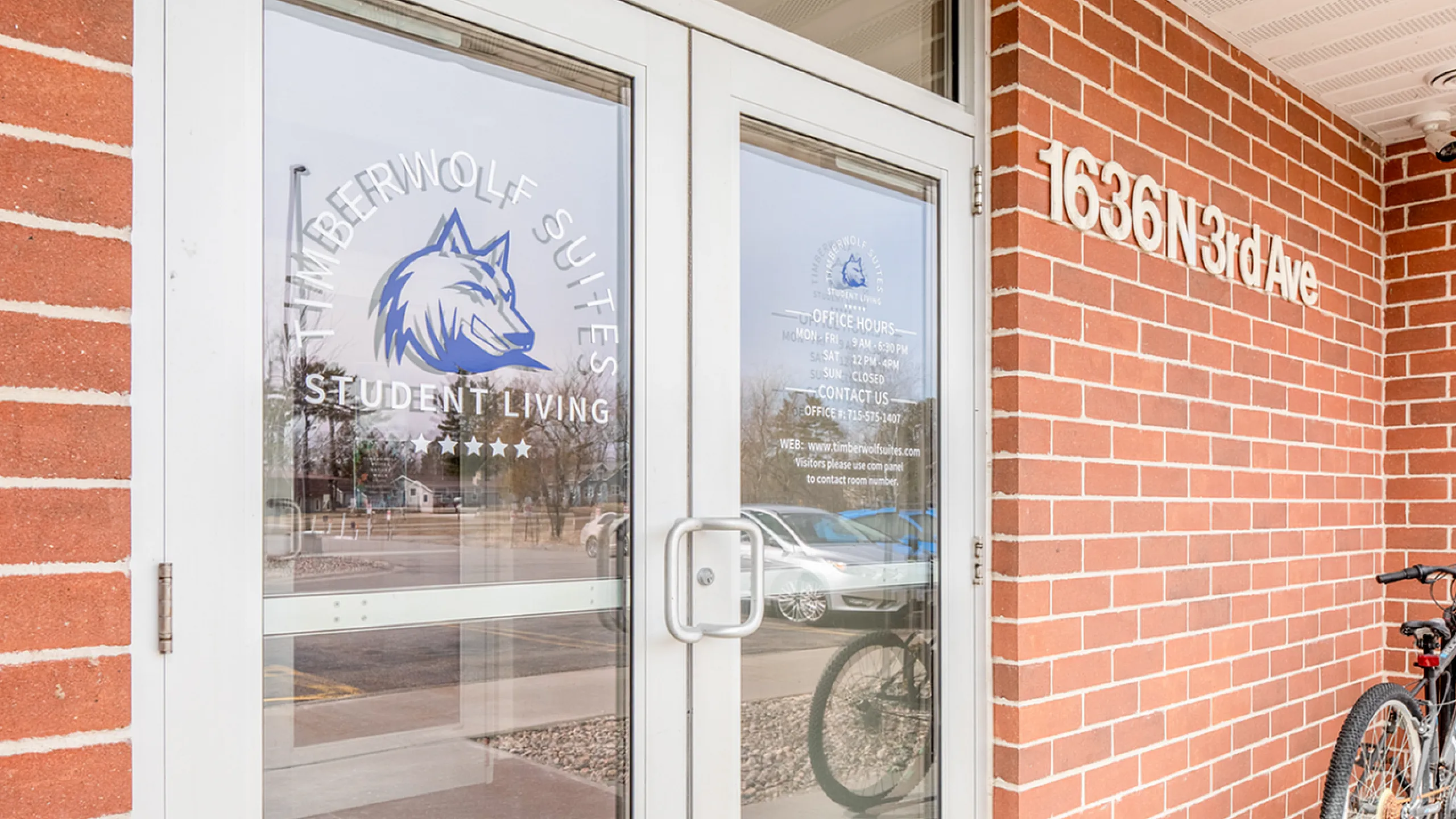 Inviting entrance to Timberwolf Suites Student Living featuring a modern glass door with brick surround at 1636 N 3rd Ave.