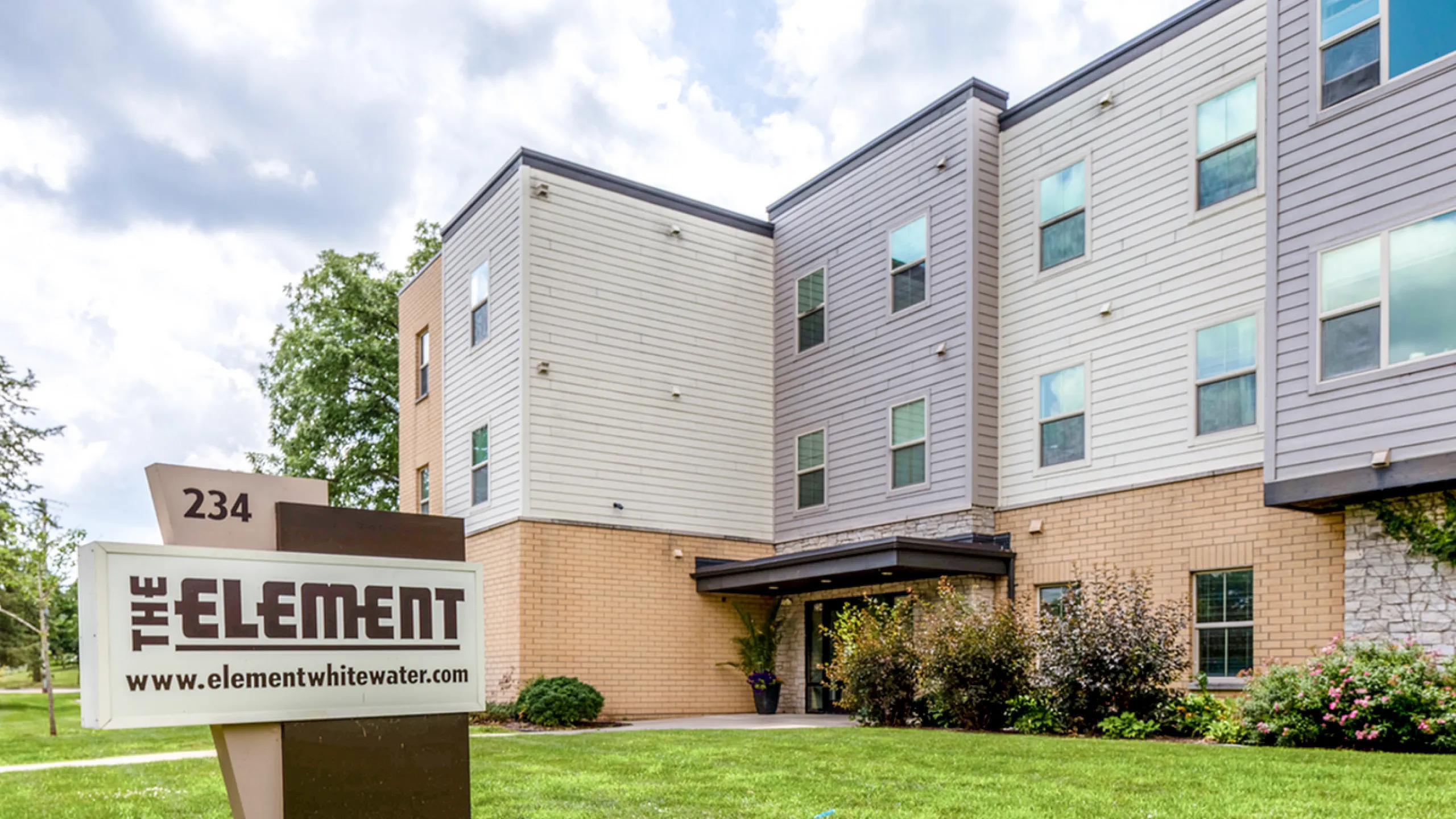 Inviting exterior view of The Element apartments, showcasing modern architecture and lush landscaped surroundings.