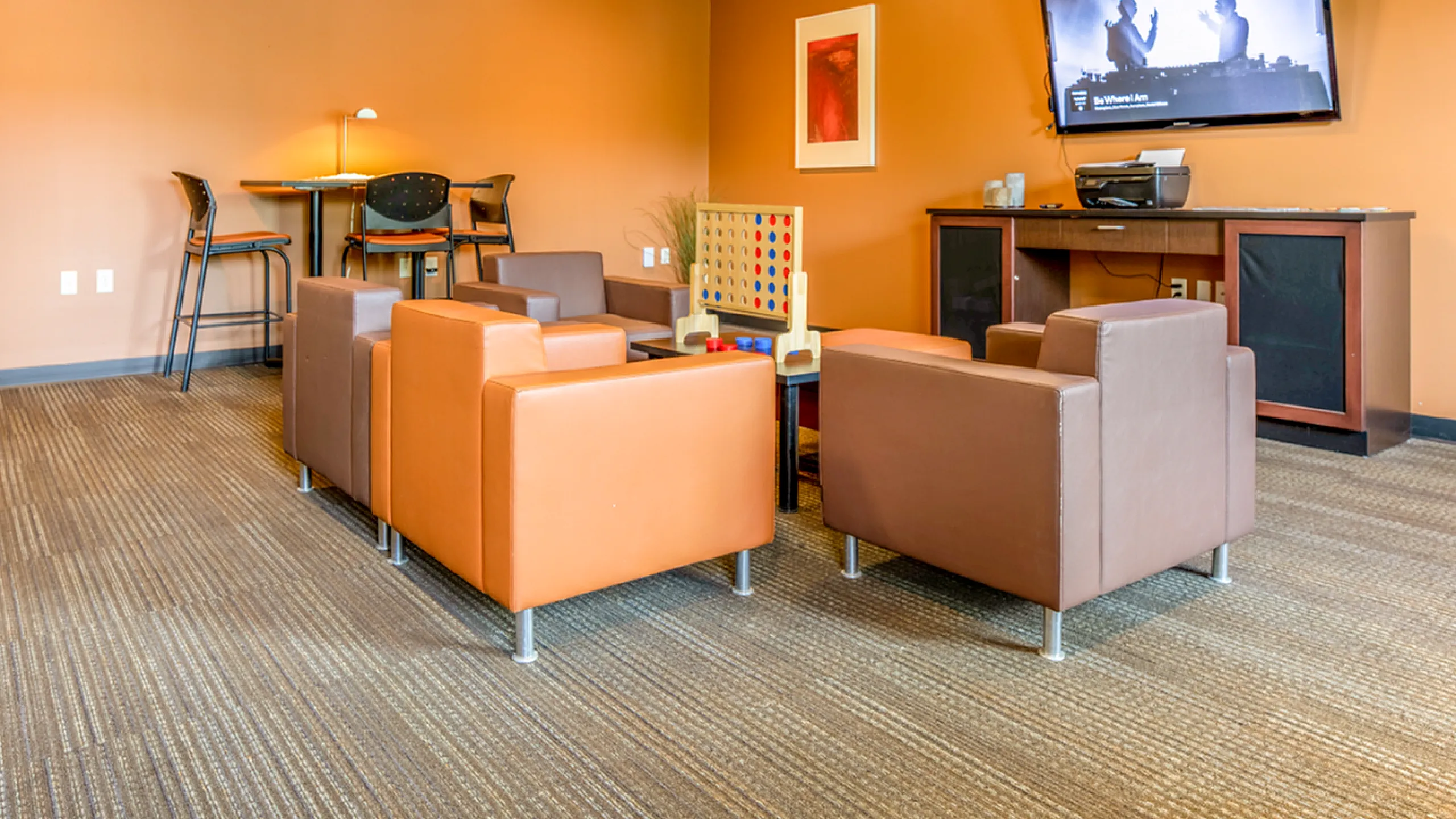 Contemporary lounge area with modern armchairs, a cozy gaming setup, and a wall-mounted TV, perfect for relaxation and entertainment.