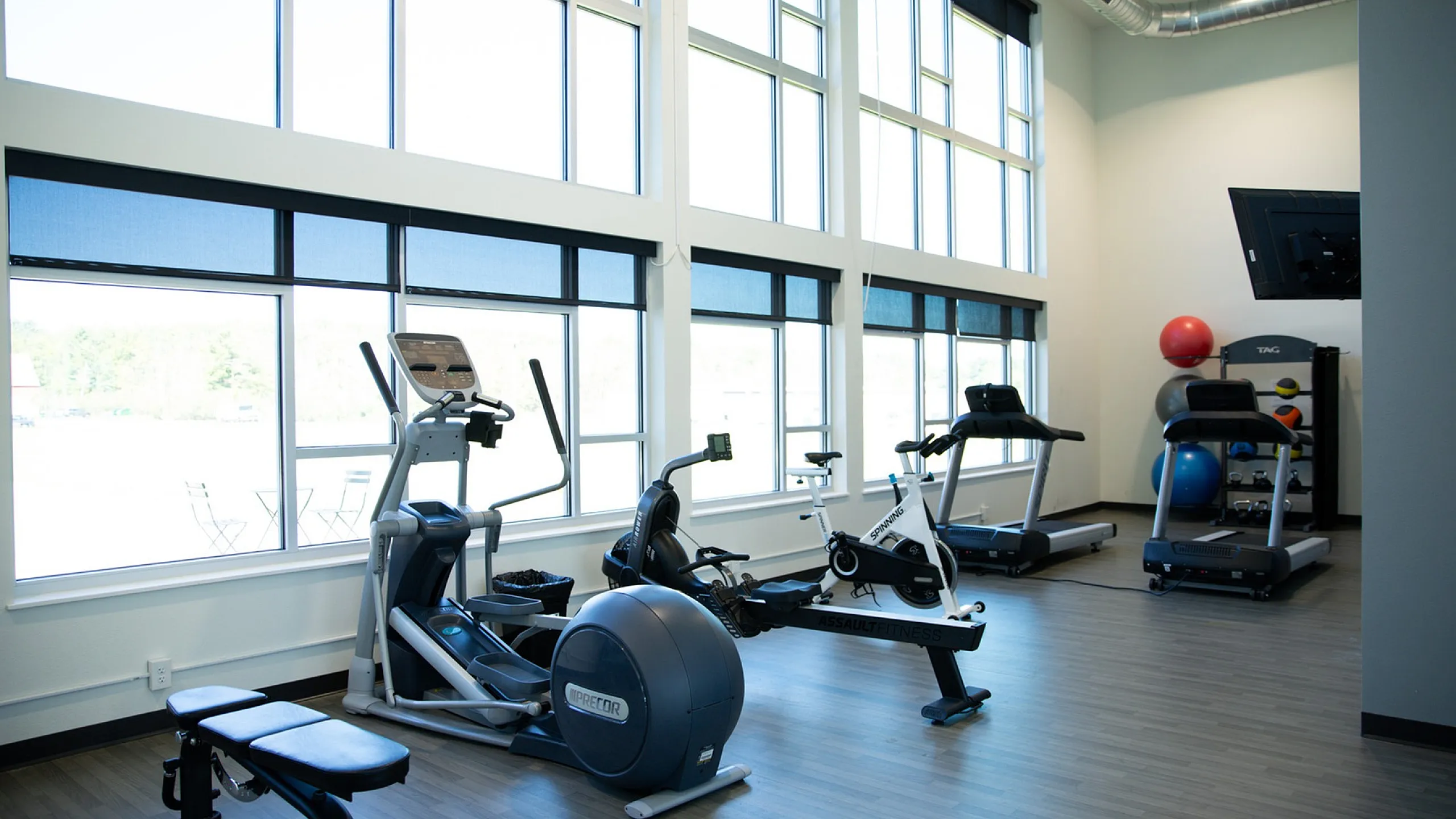 Bright and modern gym with state-of-the-art exercise equipment, featuring large windows for natural light and a sleek design.
