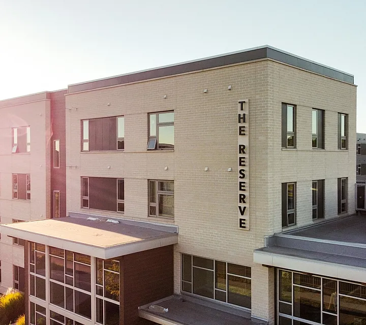 Elegant apartment building bathed in warm sunset light, showcasing modern architecture and a peaceful atmosphere at The Reserve.