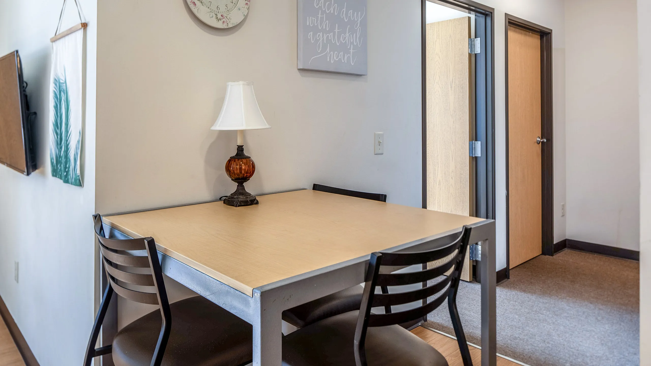 Cozy dining nook with a minimalist table, two chairs, and a charming table lamp, accented by tasteful wall decor.
