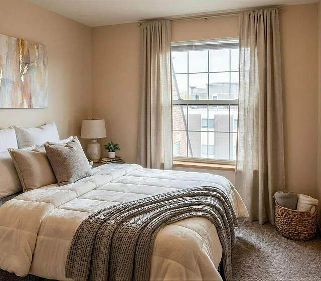 Cozy bedroom with a comfy bed, stylish artwork, and large window providing natural light for a relaxing atmosphere.