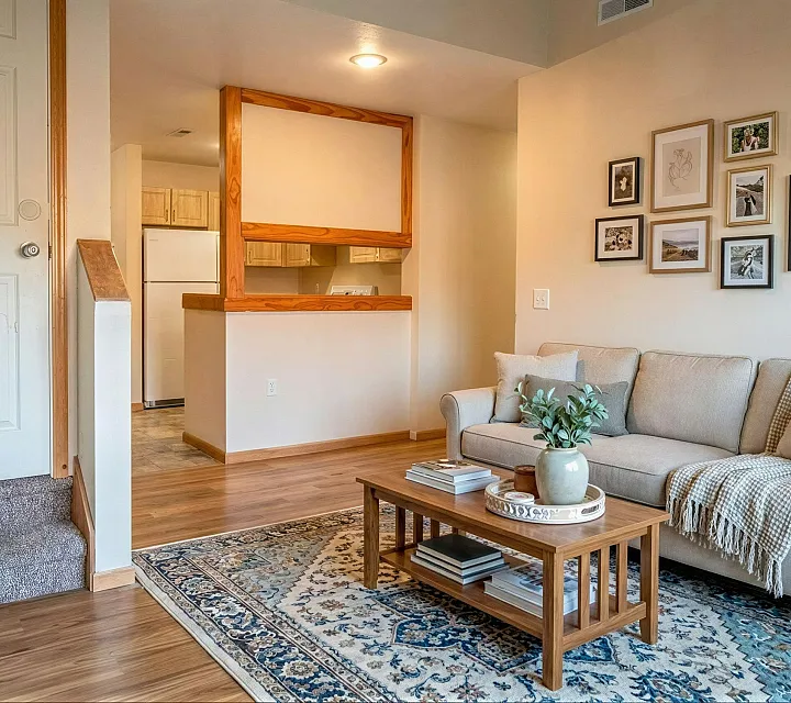 Cozy living room with stylish decor, a plush sofa, elegant rug, and a view of the open kitchen, accented with warm wood finishes and tasteful framed artworks.