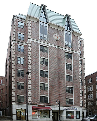 Charming urban apartment building with classic brick facade, featuring a distinctive architectural design and conveniently located retail spaces on the ground floor.