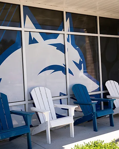 Inviting outdoor seating area with Adirondack chairs and vibrant wall art, perfect for relaxing and enjoying the ambiance.