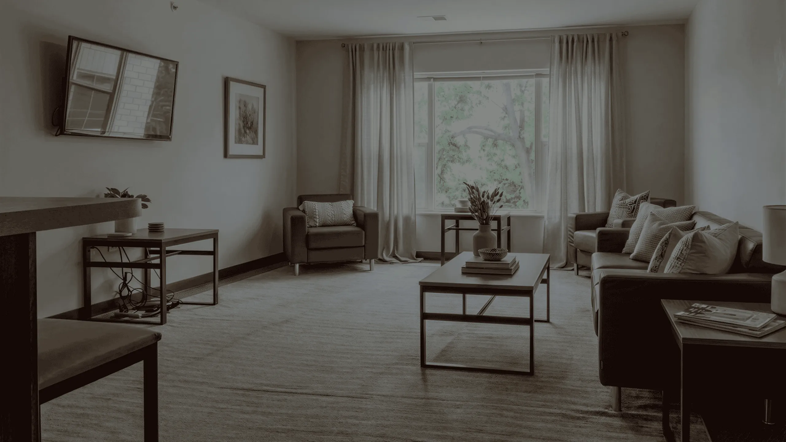 Elegant living room with contemporary furniture, large window, and cozy decor overlooking lush greenery.