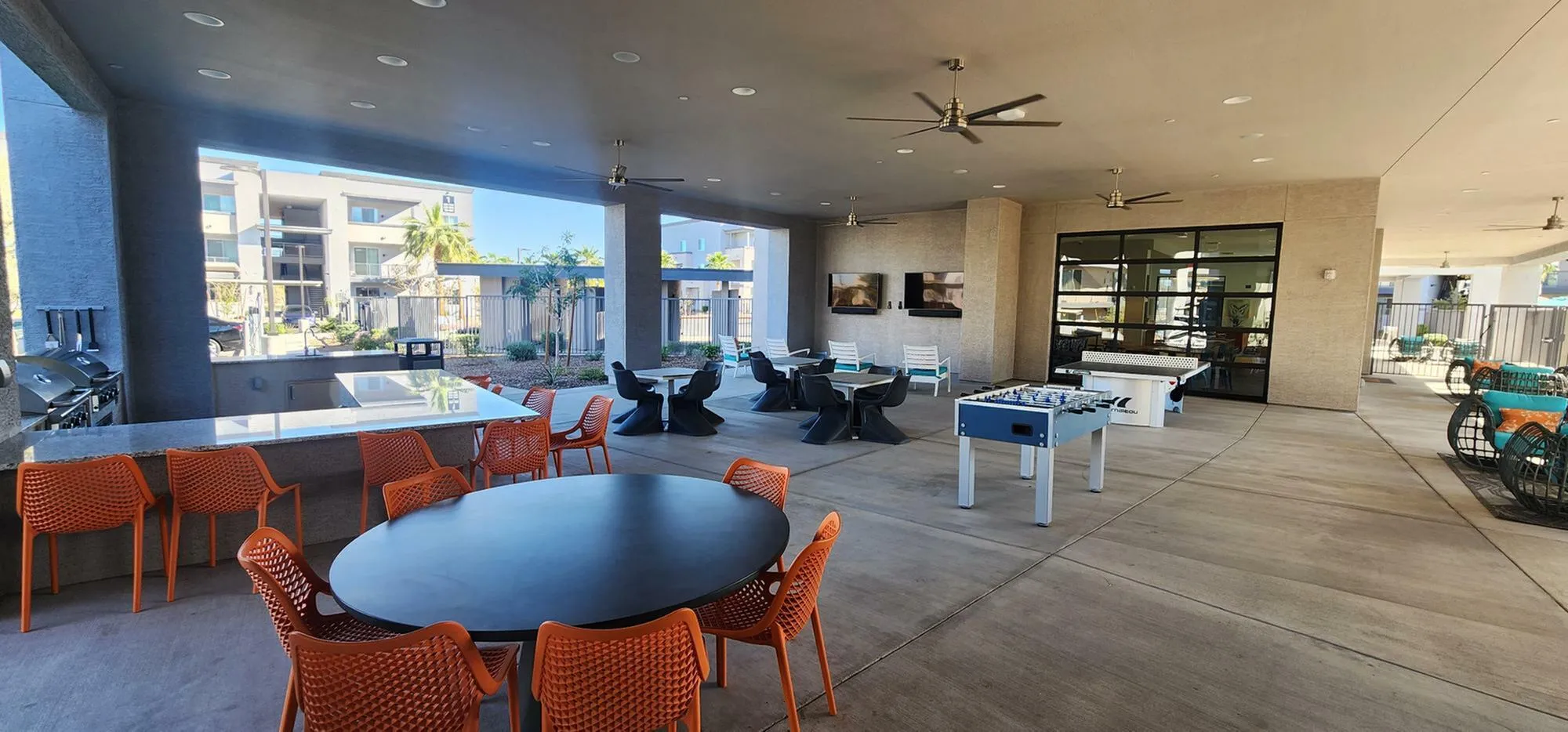 Modern outdoor entertainment area with sleek furniture, foosball tables, and a stylish dining setup, perfect for gatherings.