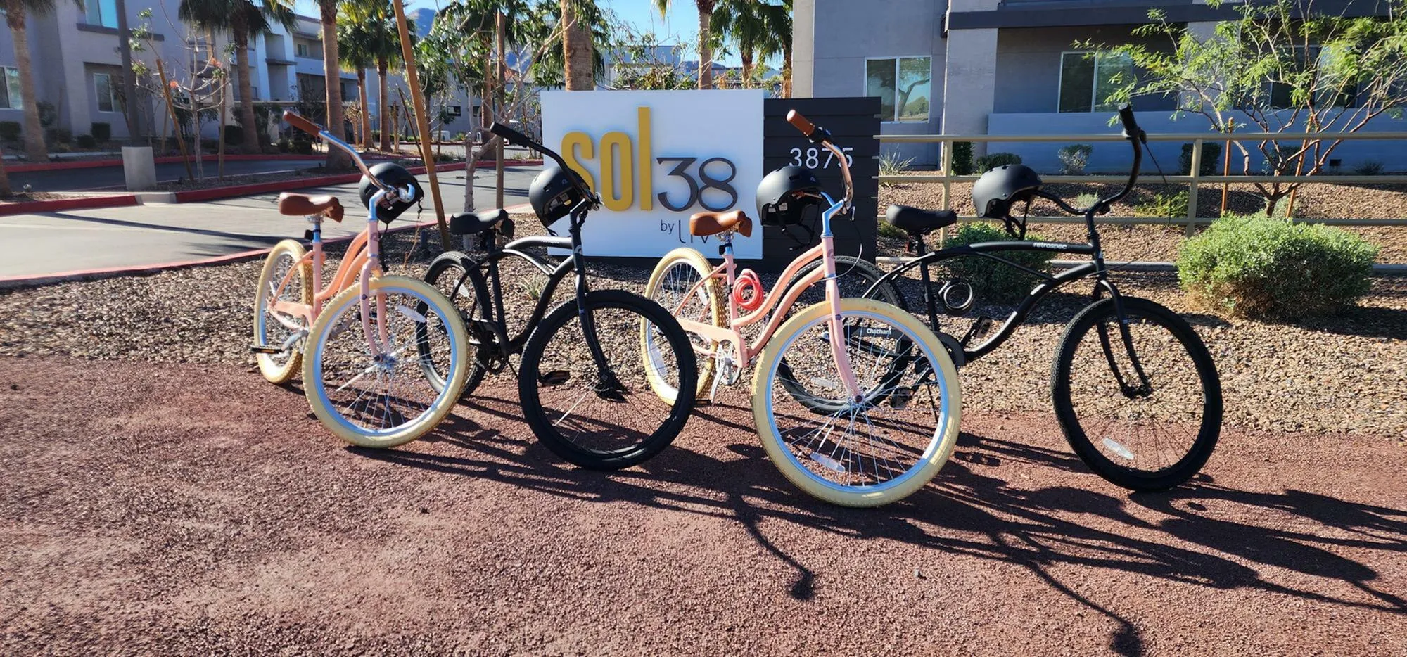 Colorful bicycles parked in front of a modern apartment complex sign under sunny skies, inviting a vibrant and active lifestyle.