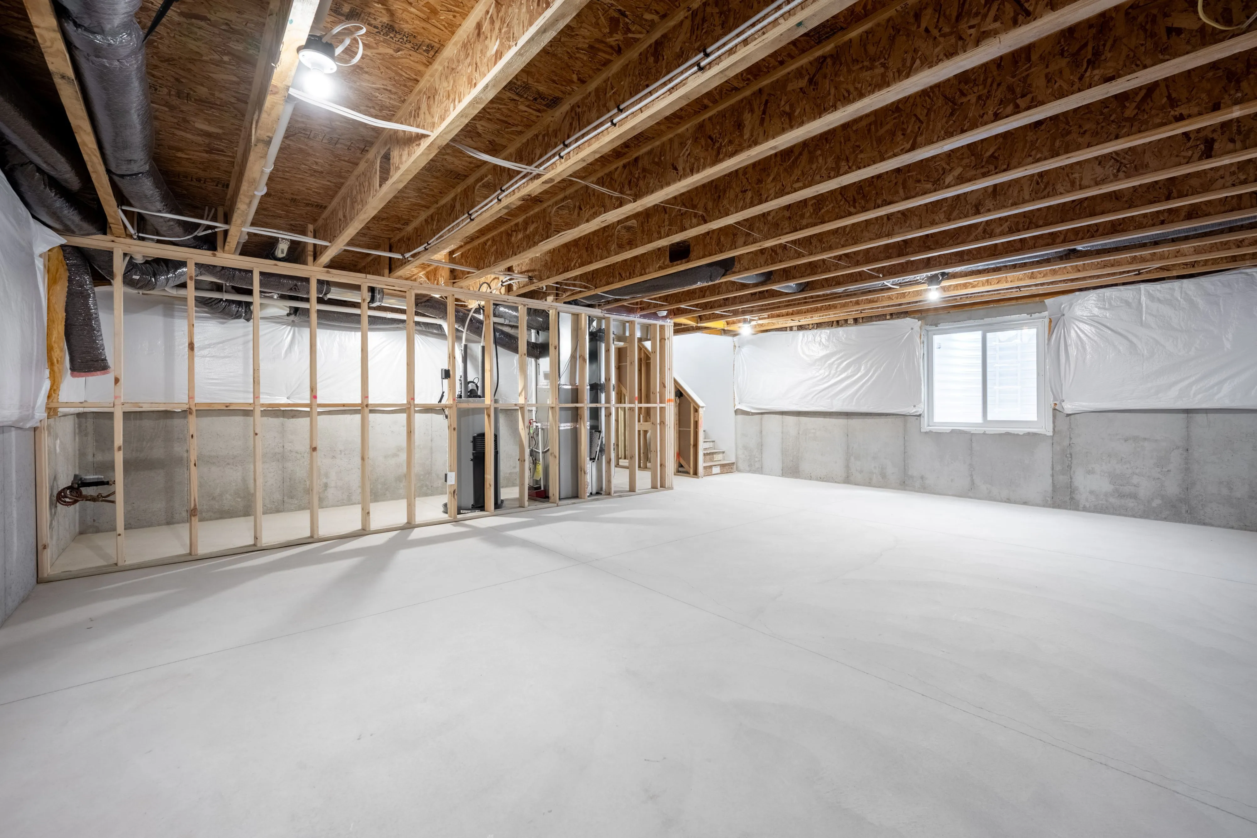 Expansive unfinished basement with open layout, potential for customization, featuring wooden framing and bright lighting.