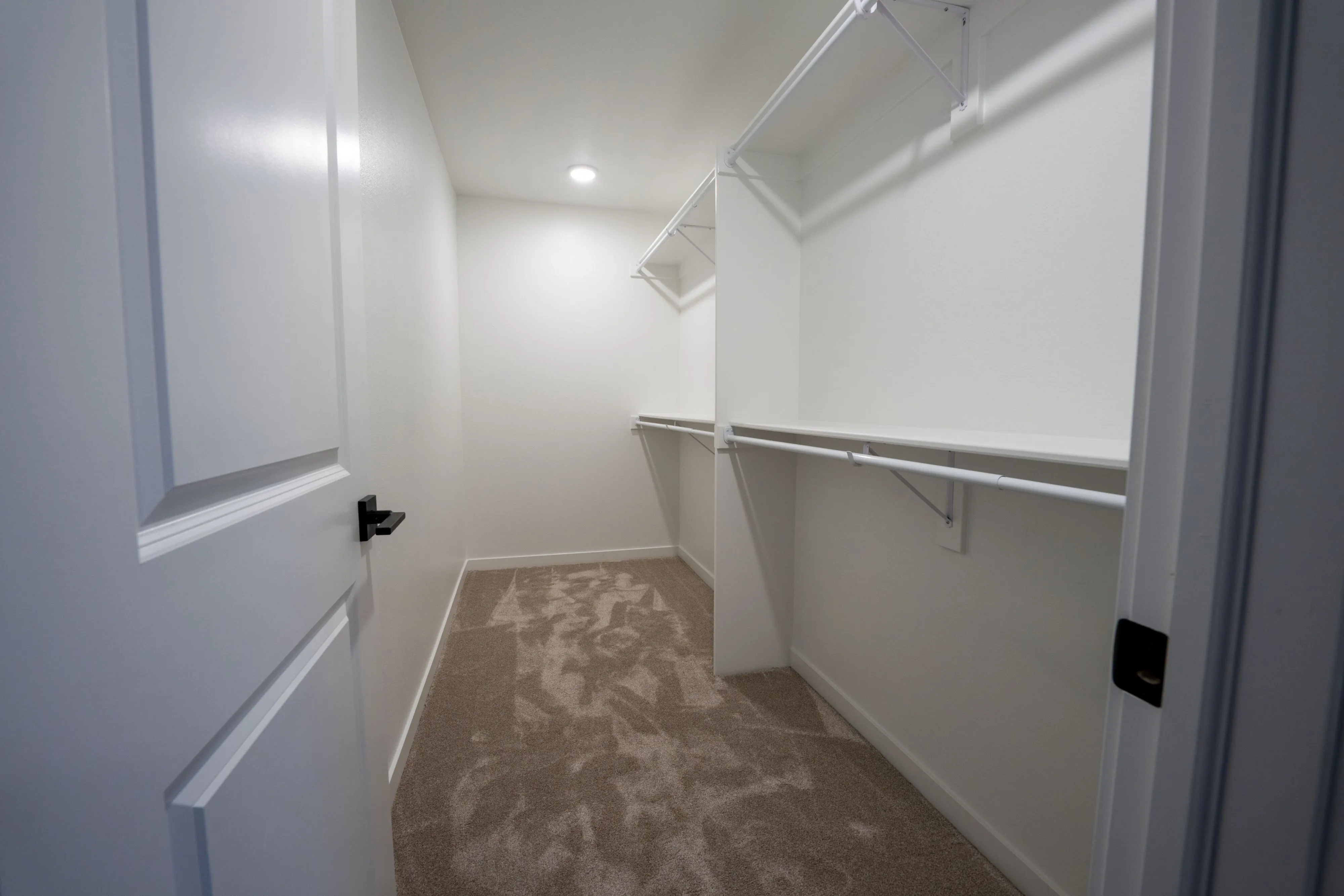 Spacious walk-in closet with sleek white shelving, perfect for organized storage and stylish living.