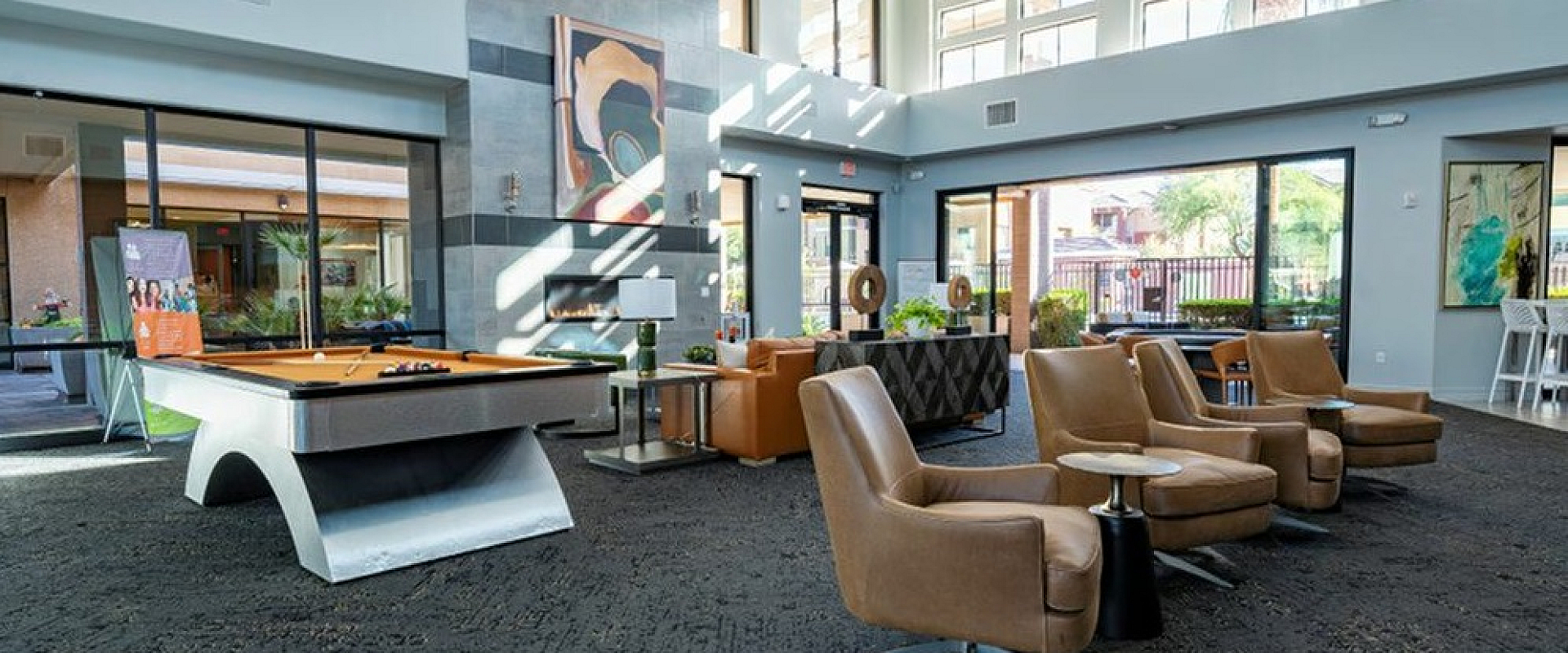 Luxurious communal lounge with modern pool table, plush seating, and bright floor-to-ceiling windows.