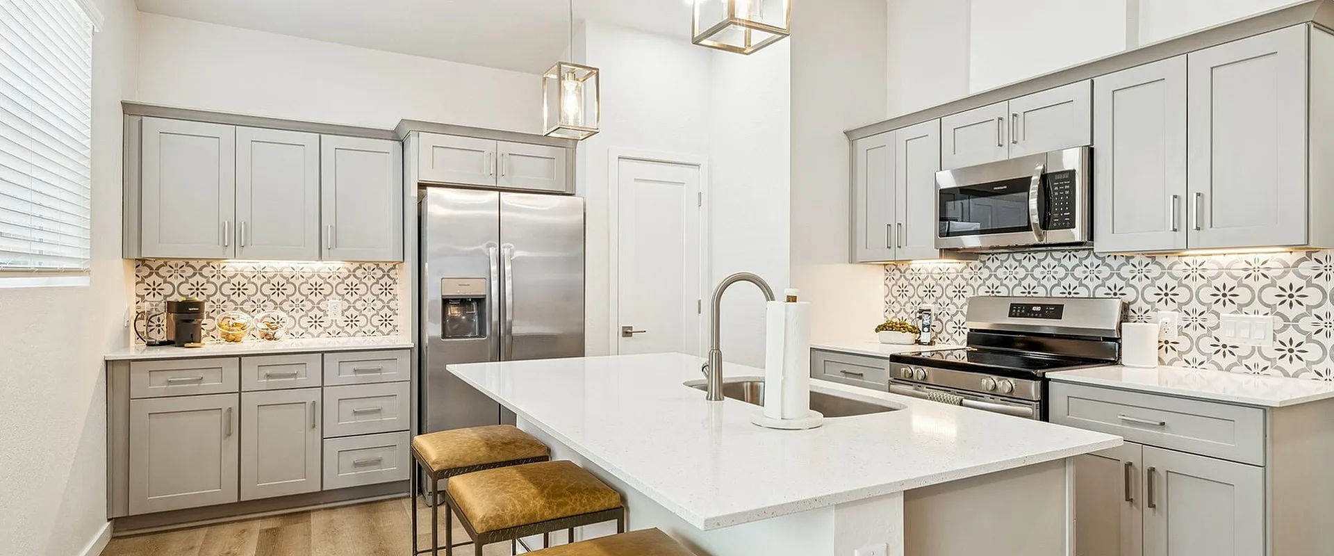 Modern kitchen with sleek gray cabinets, spacious island, and stylish pendant lighting.