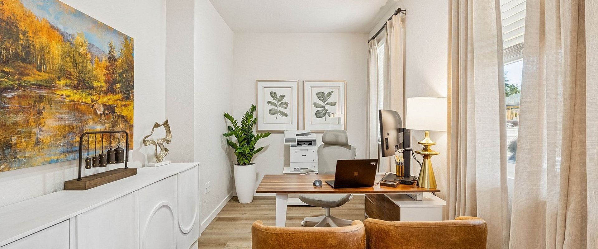 Bright and modern home office featuring elegant wood flooring, chic artwork, and cozy leather chairs.