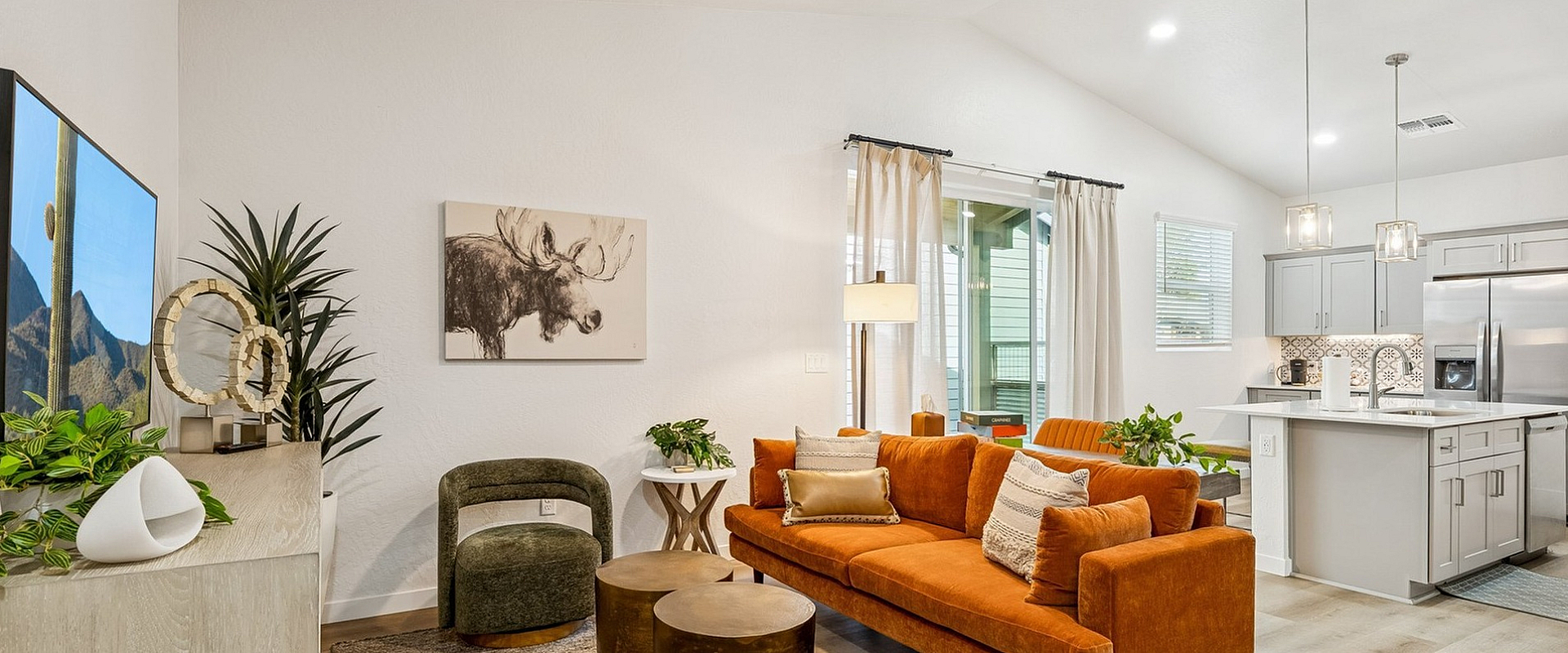 Chic modern living room with vibrant orange sofa, elegant decor, and stylish open-concept kitchen.
