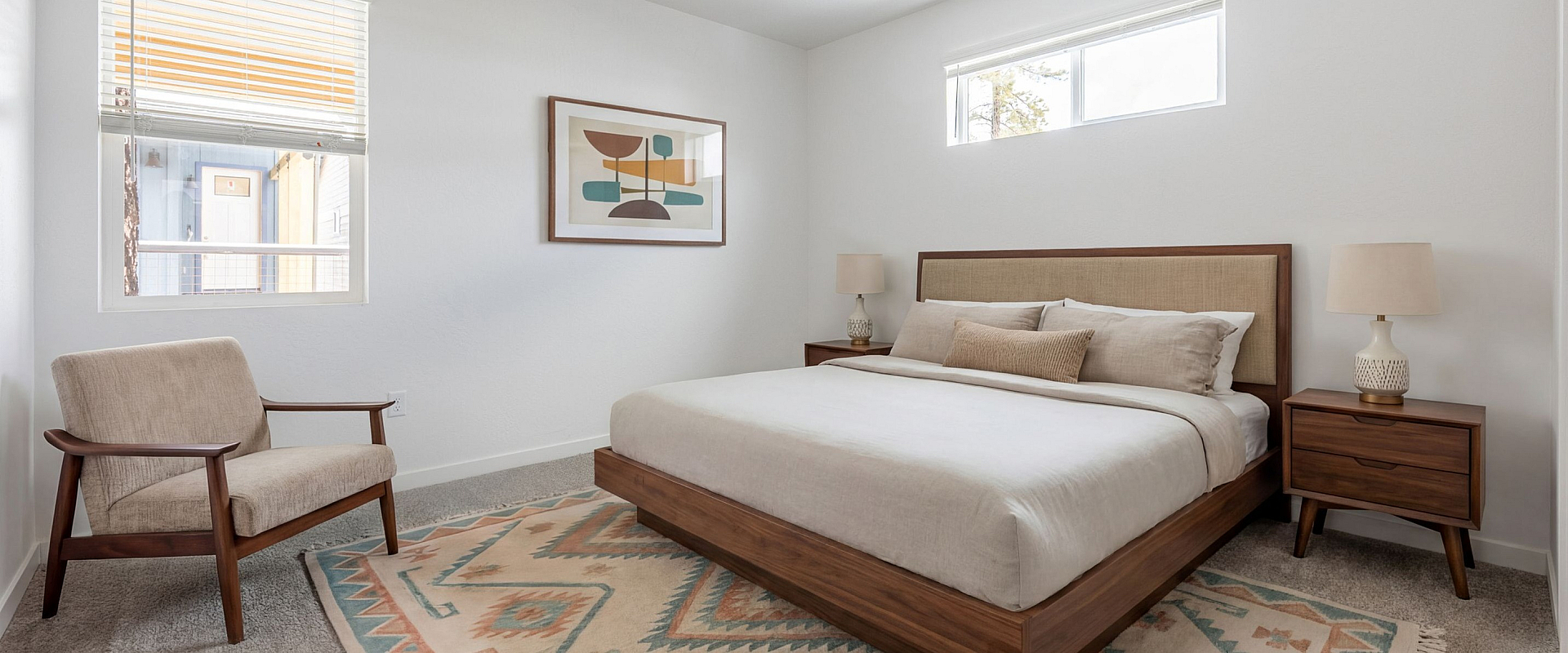 Bright and modern bedroom with sleek furniture, soft carpet, and contemporary art, creating a cozy and inviting atmosphere.