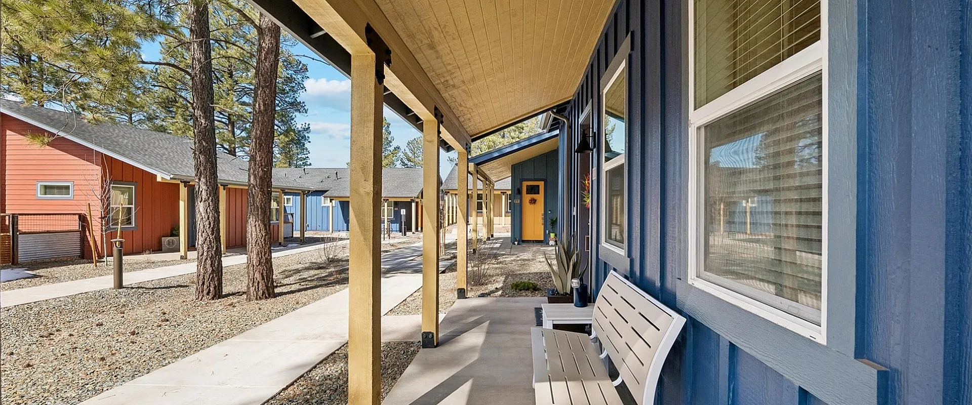 Charming exterior view of a cozy apartment community with colorful facades, modern design, and inviting outdoor seating.