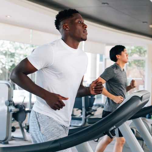 two men running on treadmills in fitness center