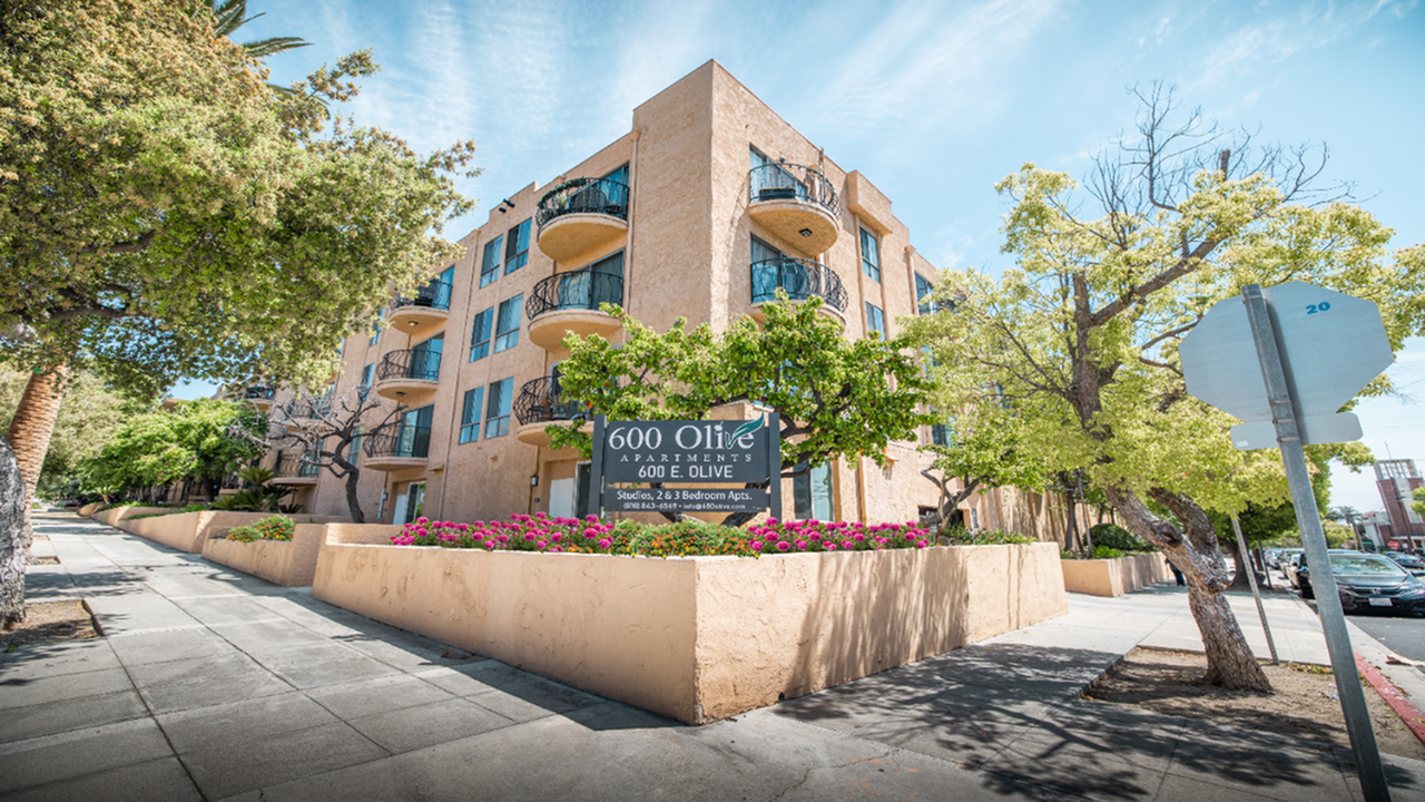 Charming 600 Olive Apartments with lush greenery, vibrant landscaping, and stylish balconies in a serene neighborhood.
