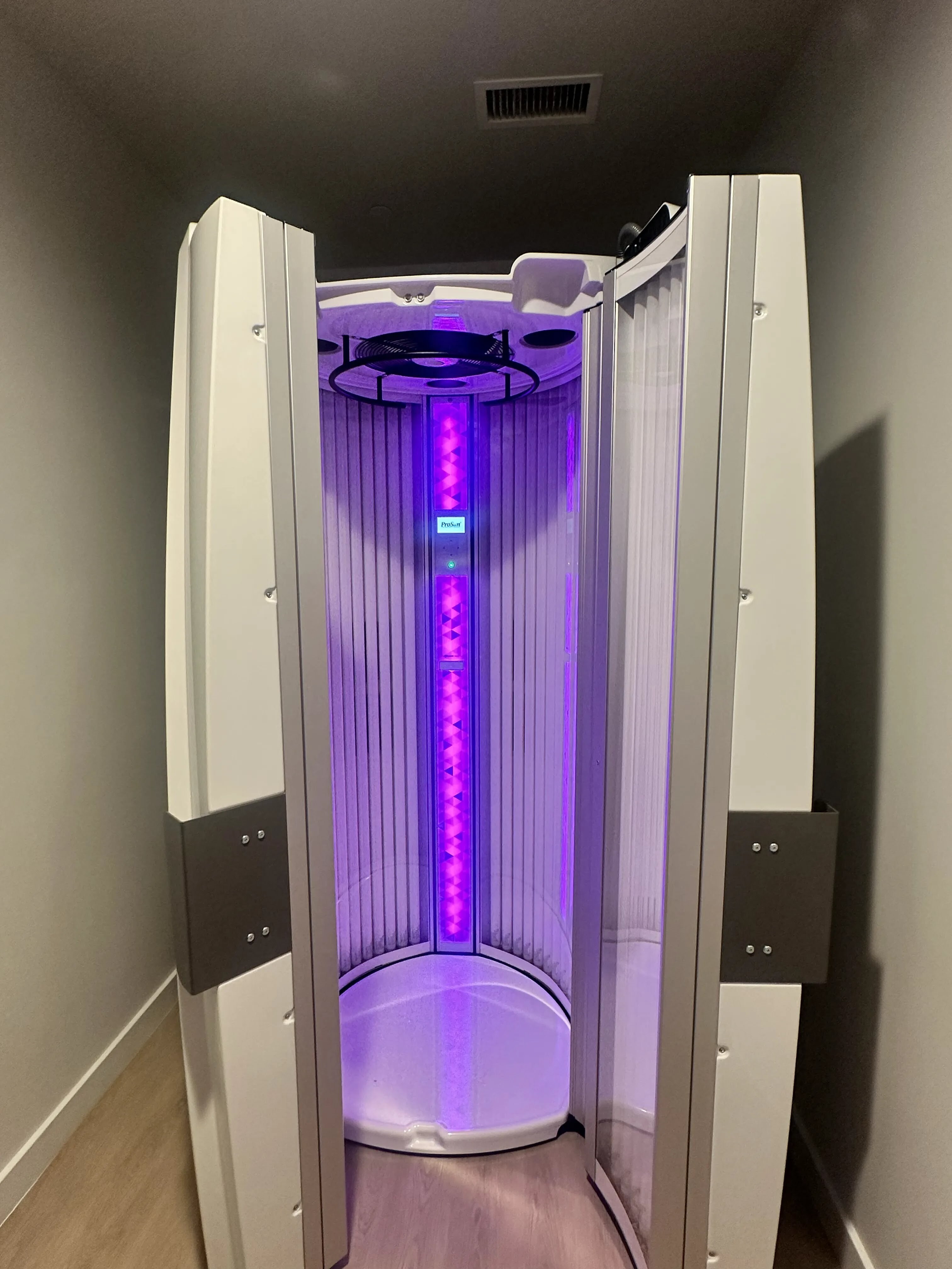 Modern UV tanning booth with sleek design and vibrant purple lighting, perfect for a relaxing home spa experience.