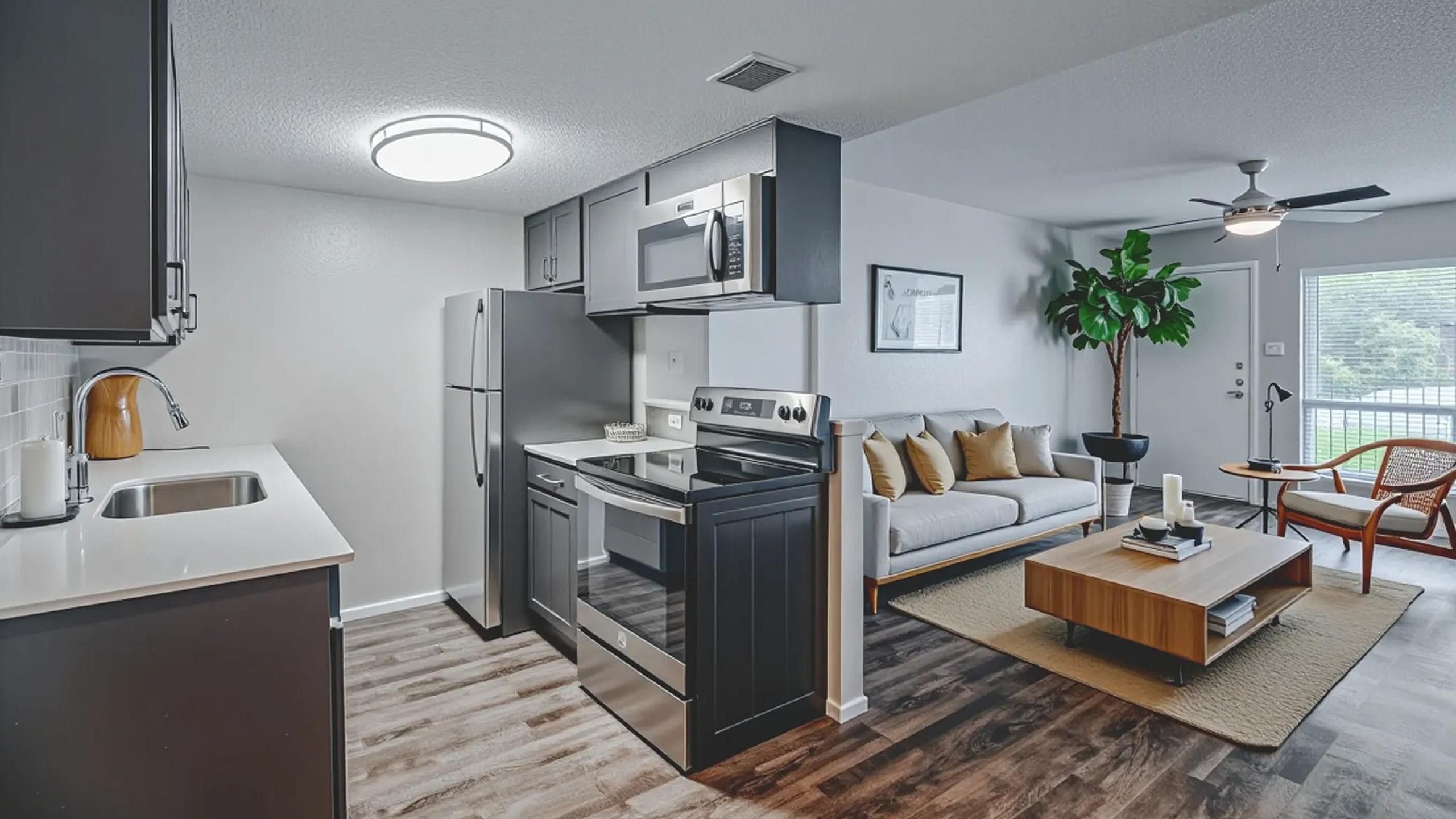 Modern open-concept kitchen and living room with sleek cabinetry, stainless steel appliances, and cozy seating area.