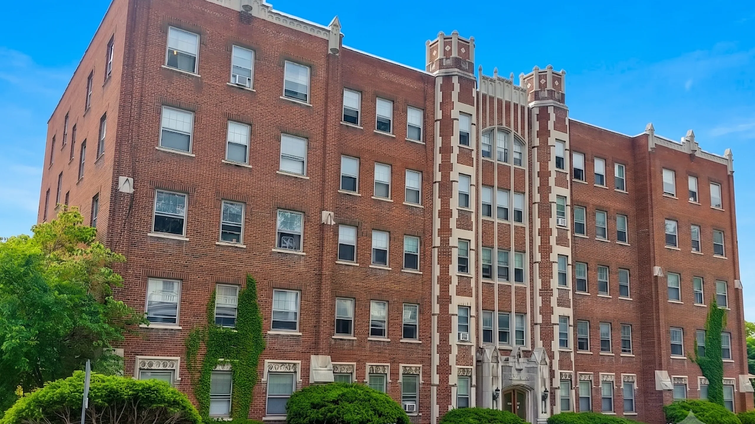 Charming historic brick apartment building with elegant architectural details and lush greenery, perfect for urban living.