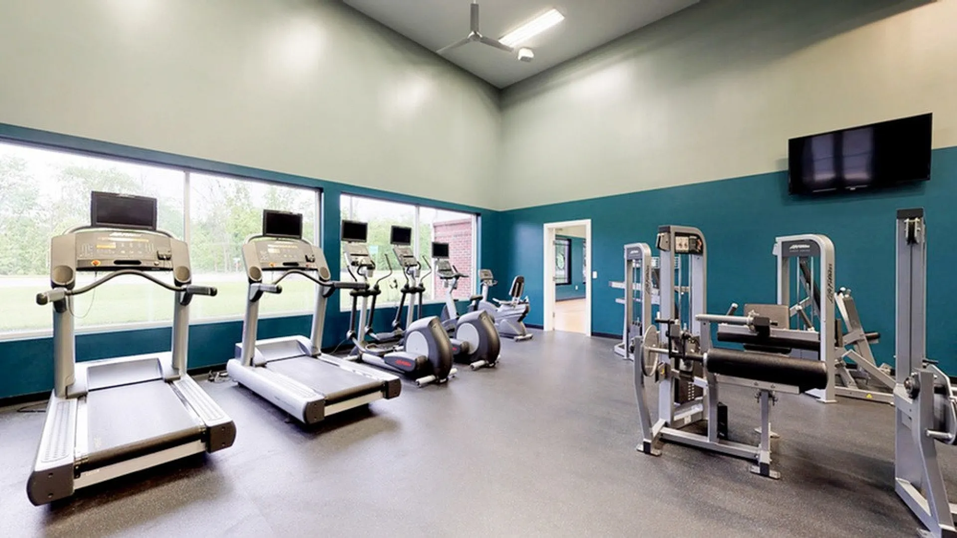 Spacious, well-lit fitness center equipped with modern treadmills and strength training machines, ideal for a healthy lifestyle.