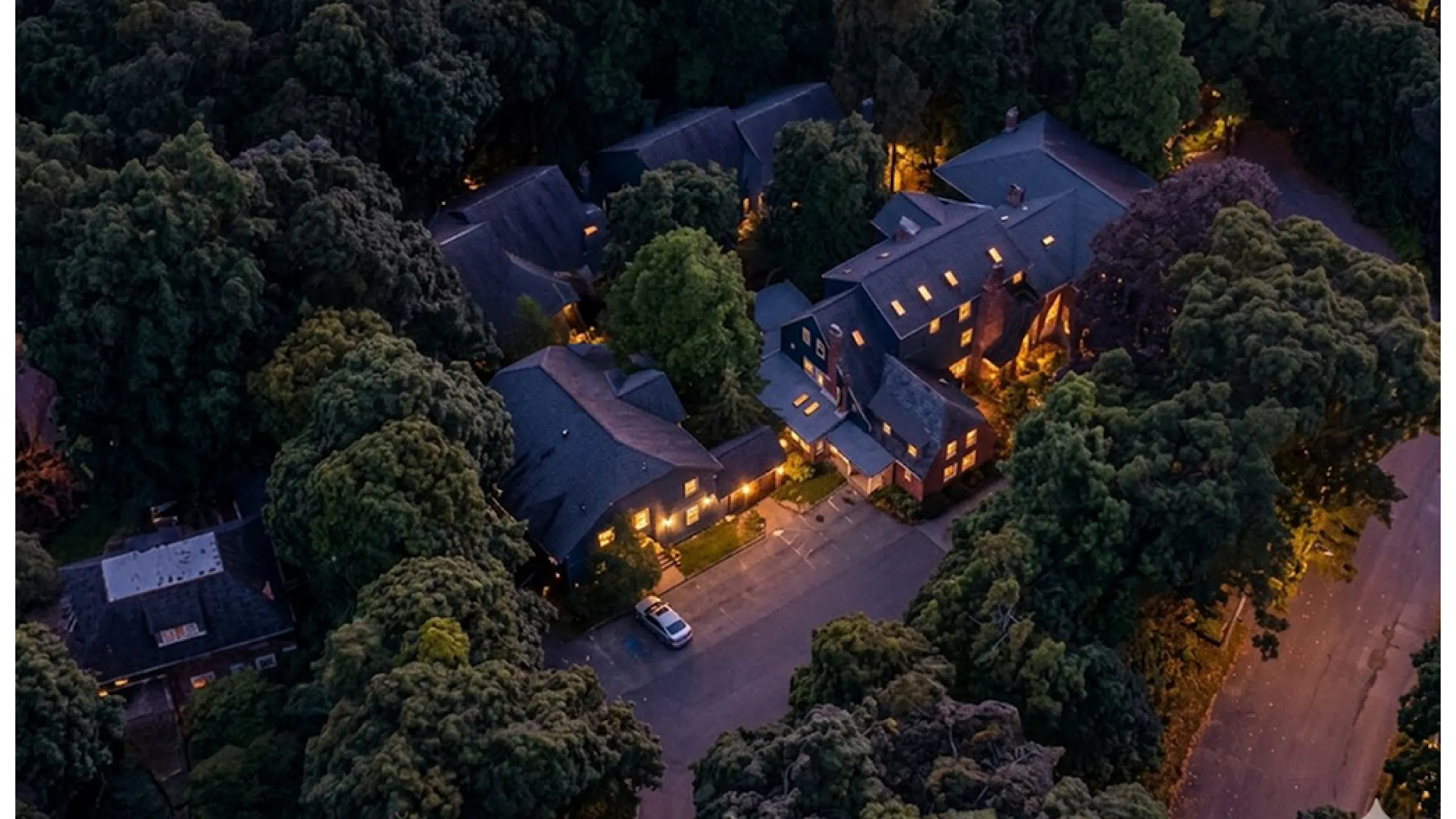 Charming aerial view of cozy apartment complex nestled among lush trees, illuminated softly for a serene ambiance.