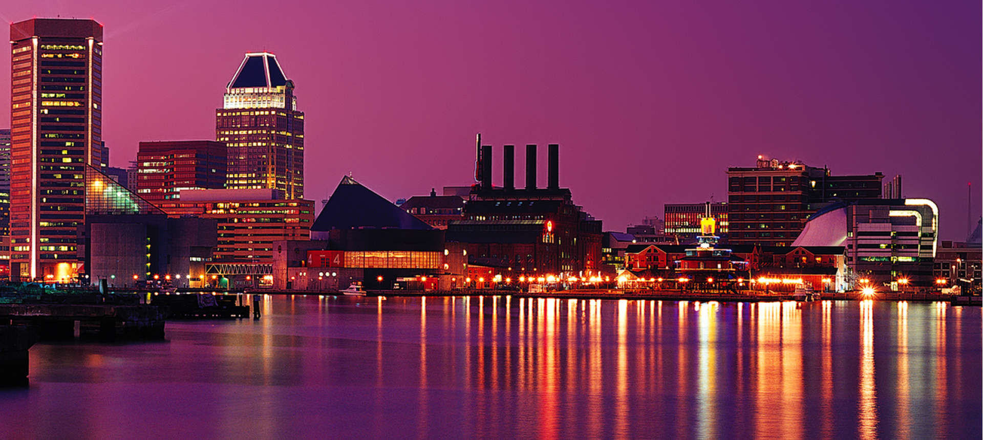 Nighttime city skyline featuring tall buildings adorned with glowing purple lights, creating a stunning urban scene.
