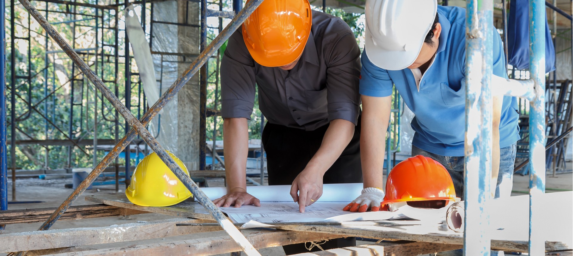 Construction workers collaborating on a building site, using tools and equipment to progress on the structure.