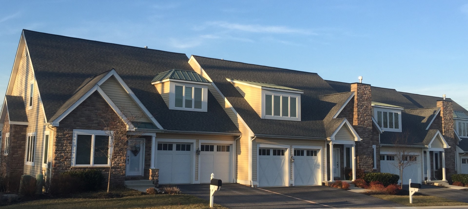 Several houses lined up, each with a garage and a driveway, typical of a residential area.