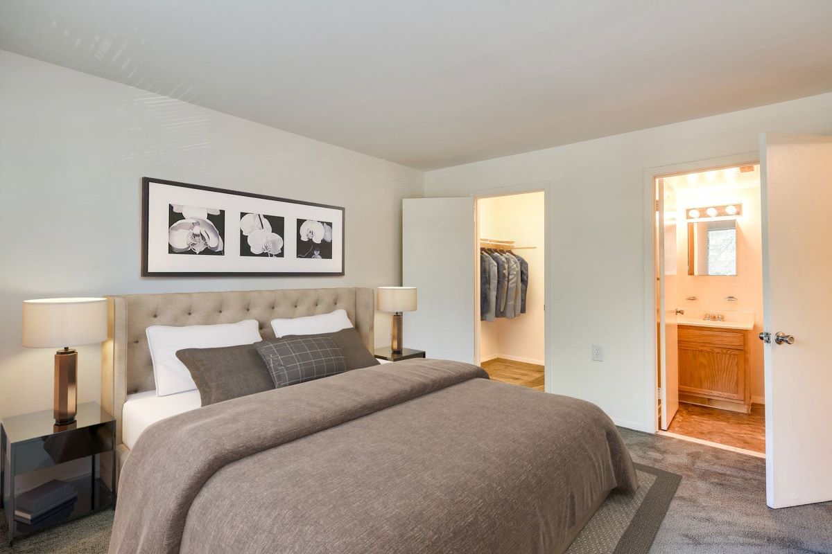 A stylish bedroom at Butler Ridge Apartments, showcasing a bed, dresser, and mirror for a welcoming atmosphere.
