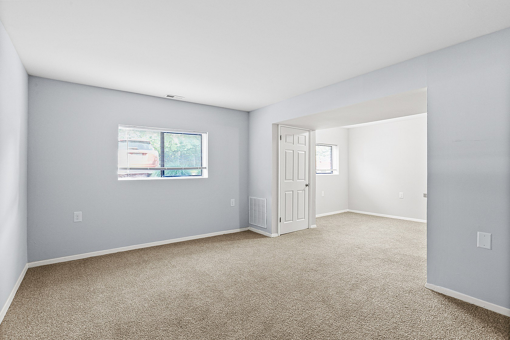 Bright, spacious room featuring soft carpet flooring and large windows with abundant natural light.